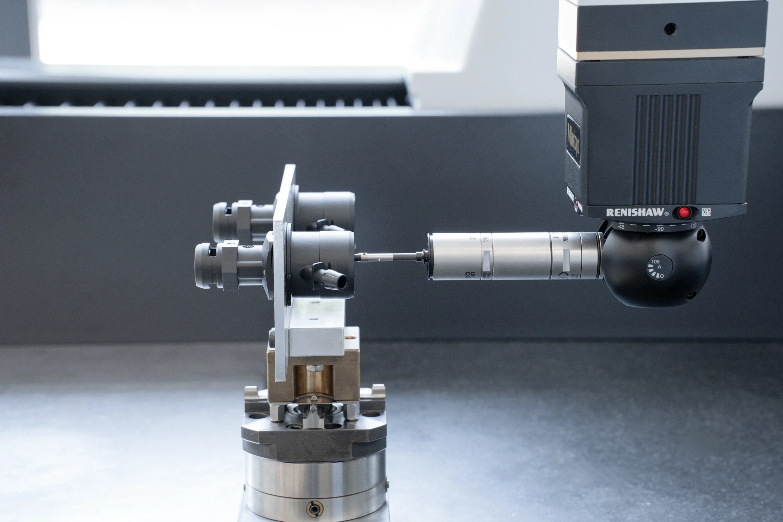 Palpeur à contact Renishaw d’une machine à mesurer contrôlant une pièce métallique bridée sur un montage.